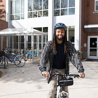 一个学生在橡树园前骑自行车. 